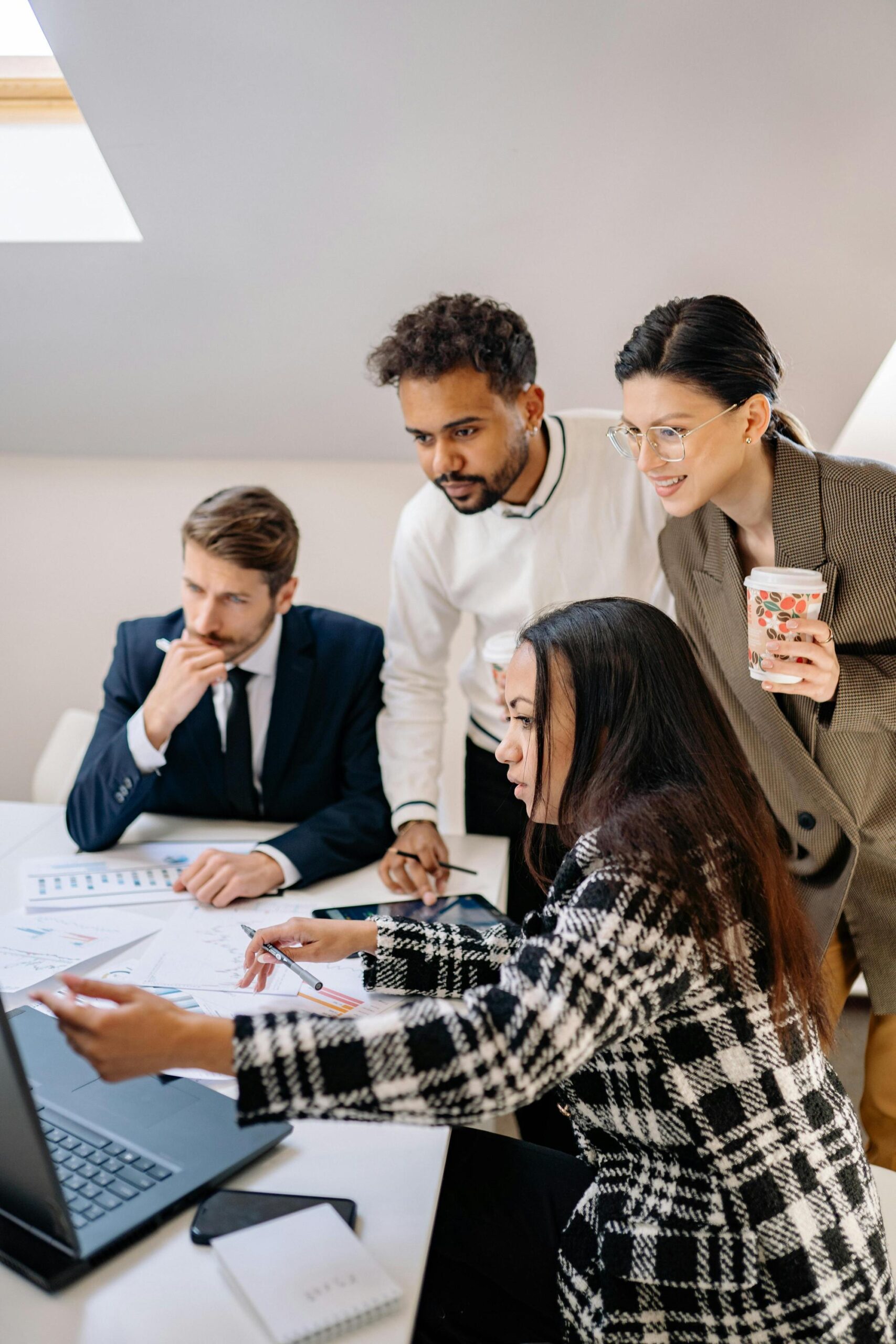 Diverse business team collaborating around a laptop during an AI strategy meeting.